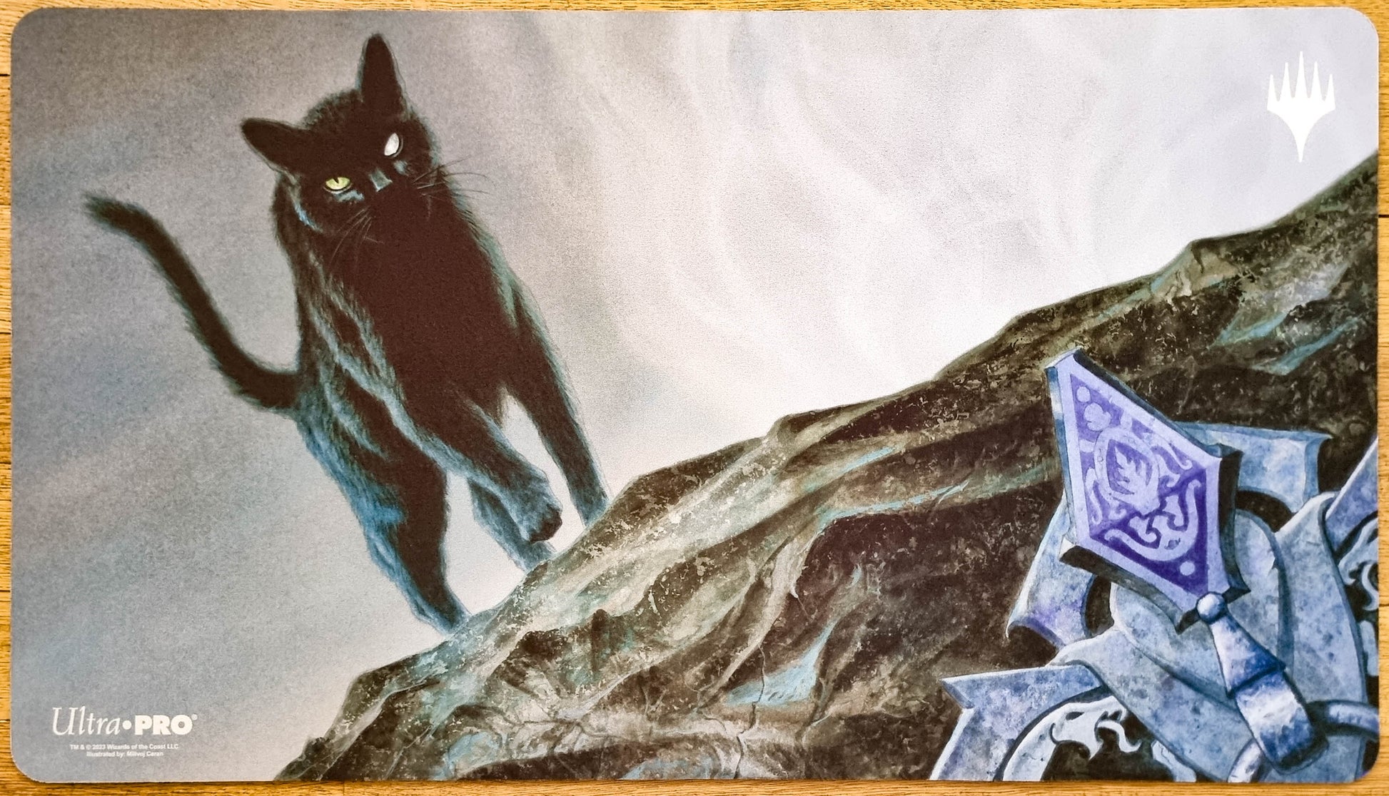 Cauldron Familiar MTG playmat featuring a black cat on a twisted branch, illustrated by Milivoj Ćeran for Throne of Eldraine.