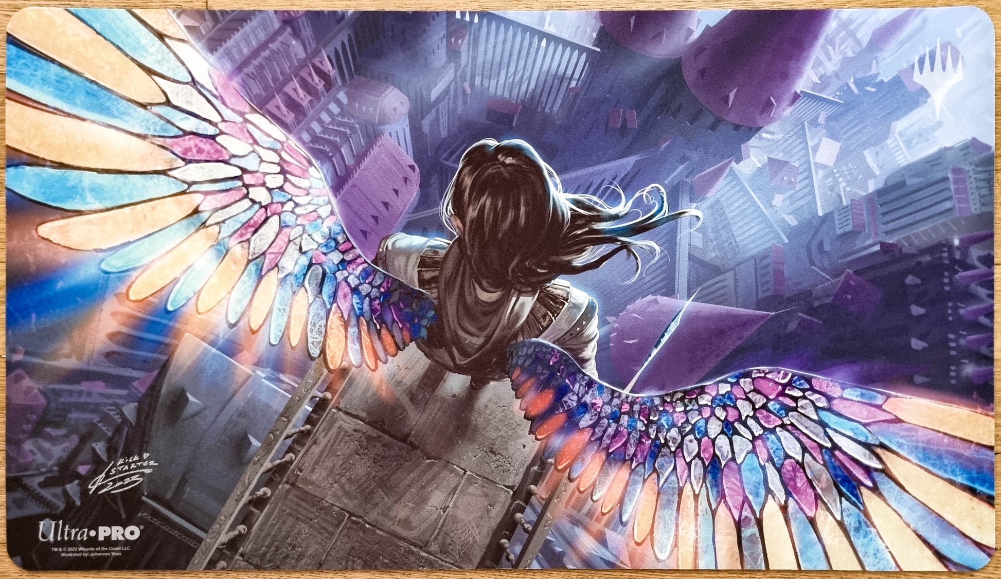 Signed Gift of Orzhova MTG playmat by Johannes Voss showing a winged figure with stained-glass wings flying over a dark cityscape.