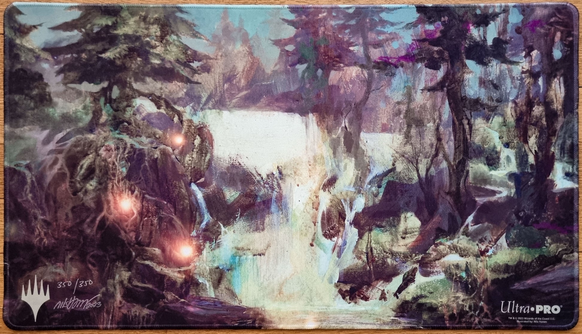 Signed and stitched Island MTG playmat by Nils Hamm showing a misty woodland waterscape with glowing lights, trees, and waterfalls.