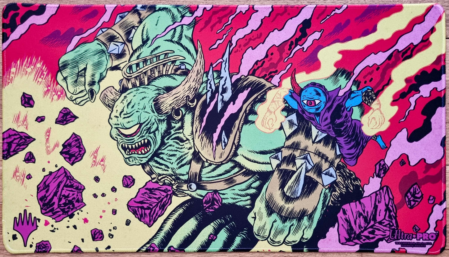 Stitched Okaun and Zndrsplt MTG playmat by Alexis Ziritt showing a green cyclops and blue homunculus in a vivid comic-style chaos scene.
