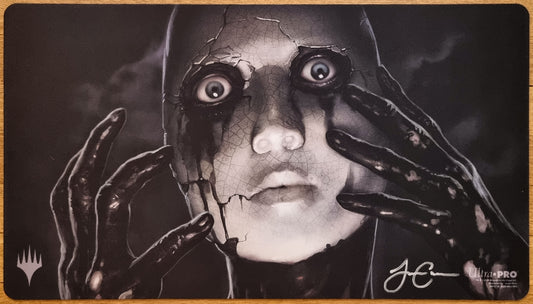 Signed Phyrexian Unlife MTG playmat by Jason Chan showing a cracked porcelain-like face with dark hands in a monochrome horror scene.