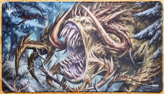 Signed Tarmogoyf MTG playmat featuring Filip Burburan’s Ultimate Masters artwork, showing the horned creature in a snowy forest with stitched black edges.